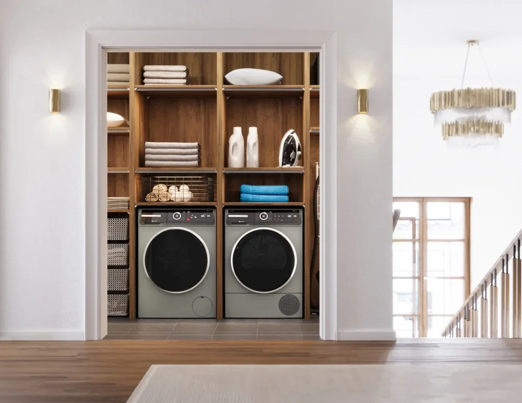 High-end washer repair on a sage-green front-load unit paired with a matching dryer inside a custom wood-panelled laundry alcove.