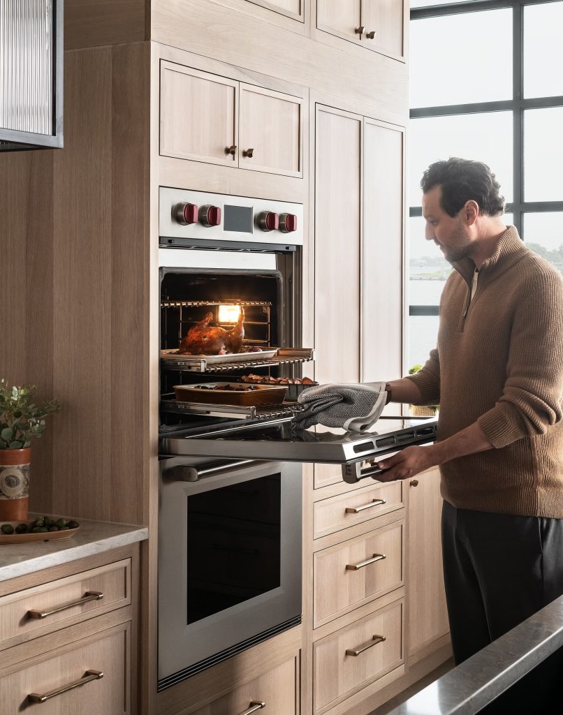 Wolf wall oven repair on a built-in double oven with red knobs, opened mid-roast in a luxury Orange County kitchen.